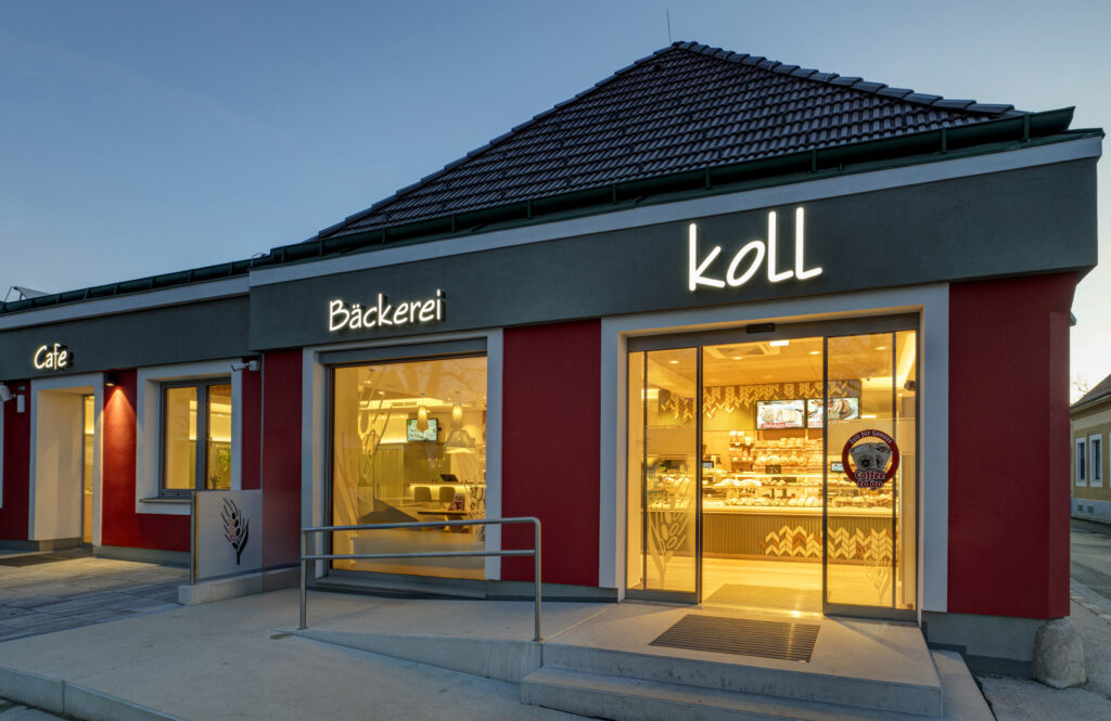 Die Fassade wurde für ein barrierefreies Eingangsportal geöffnet, wodurch das handwerkliche Backsortiment bereits von außen und beim Eintritt sichtbar wird. © Michaela Begsteiger / AICHINGER