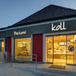 Die Fassade wurde für ein barrierefreies Eingangsportal geöffnet, wodurch das handwerkliche Backsortiment bereits von außen und beim Eintritt sichtbar wird. © Michaela Begsteiger / AICHINGER