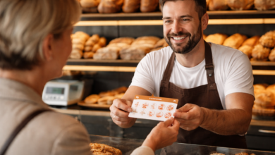 Ein Bäcker nimmt an der Brottheke den vollständig abgestempelten Sammelpass einer Kundin entgegen – Kundenbindung im handwerklichen Alltag. © Bild: KI-generiert/ÖBKZ