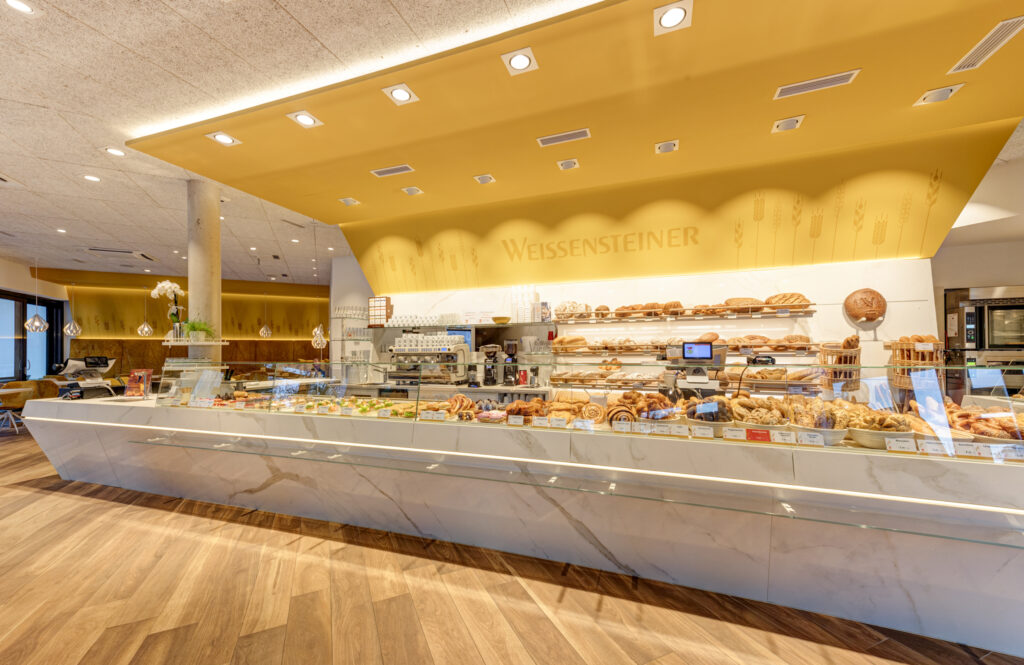 Diese Farben strahlen Wärme, Optimismus und Freundlichkeit aus. Sie ziehen sofort die Aufmerksamkeit auf sich und schaffen ein einladendes Ambiente. Gelb und Orange sind ideal für Eingangsbereiche, Schaufenster oder To-go-Angebote und Snackzonen. Es ist zu empfehlen, ein warmes Gelb zu verwenden.© Michaela Begsteiger